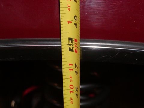 1991 Ford Bronco - A tape measure is held against the body of a red vehicle, indicating a measurement of approximately 49 inches.