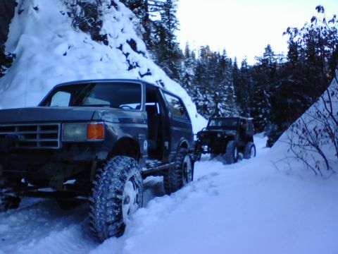 1987 Ford Bronco - Two off-road vehicles, a Ford Bronco and a Jeep, navigate a snowy trail.
