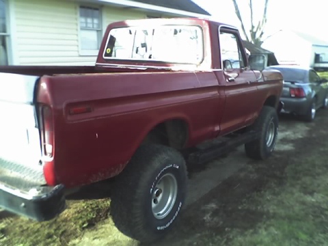 1979 Ford F-150 - This red 1979 Ford F-150 pickup truck is seen from a 3q-front angle, parked next to another vehicle.