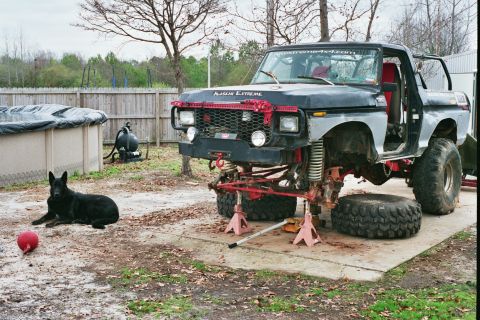 1978 Ford Bronco - A modified 1978 Ford Bronco sits jacked up in a yard, undergoing repairs or modifications.
