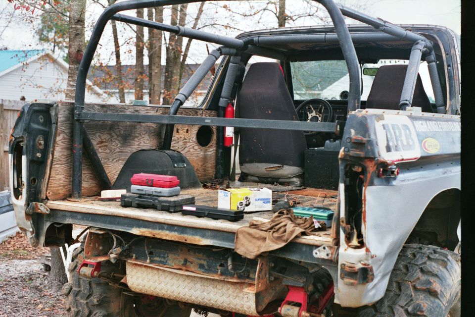 Back of a modified off-road vehicle with a roll cage, tools, and seats visible. Some text on the side reads 'ARB'