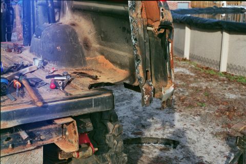 1978 Ford Bronco - The rear section of a vehicle shows significant rust and damage, with tools scattered in the bed.