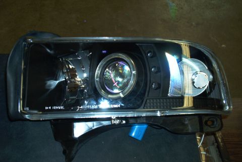 2001 Dodge 1500 - A black projector headlight assembly with chrome accents is shown, likely a replacement part.