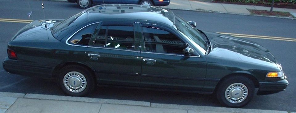Dark green 1997 Ford Crown Victoria sedan parked curbside, side view