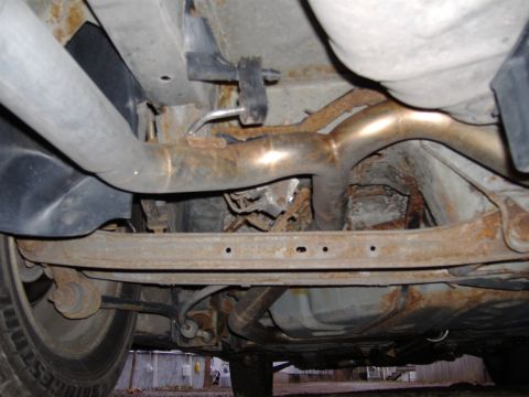 1998 Ford Taurus - Underside view of a car's exhaust system and suspension, showing significant rust and wear.