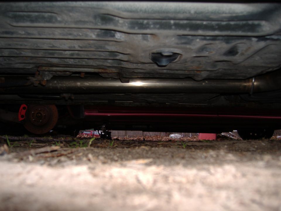 Underside view of a car showing the exhaust system and a rusty brake rotor