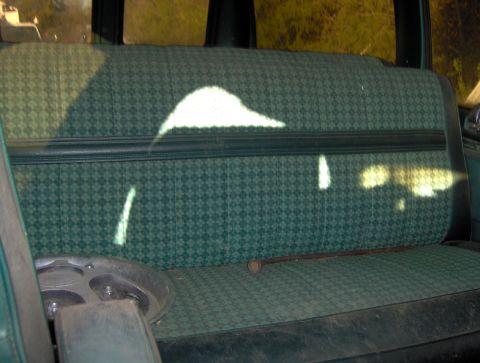 1978 Ford Bronco - Interior view of a vehicle's green patterned seat with a hubcap and rod.