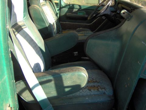 1978 Ford Bronco - Interior view of a green vehicle with worn seats and dashboard.