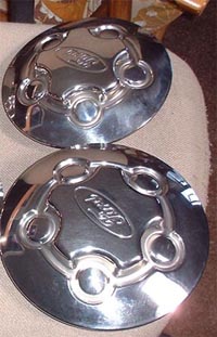 1997 Ford Crown Victoria - Two chrome Ford hubcaps are shown, each with the Ford logo in the center.