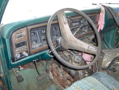 1978 Ford Bronco - The interior of a green 1978 Ford Bronco, with a focus on the dashboard and steering wheel, shows signs of wear and tear.