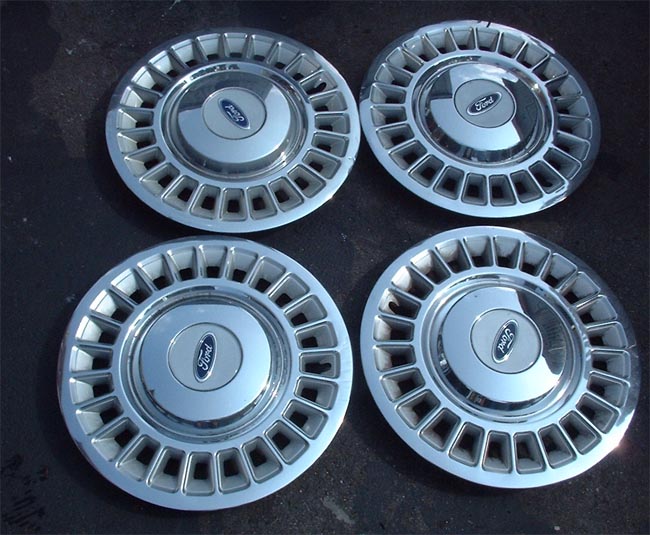 Four Ford hubcaps with blue oval logo
