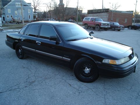 1992 Ford Crown Victoria - This 1992 Ford Crown Victoria sedan is captured in a 3q-front view, parked on asphalt with other vehicles in the background.