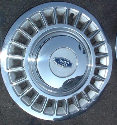 1997 Ford Crown Victoria - Chrome Ford hubcap with blue oval logo. Part of a set, another is visible on the right.