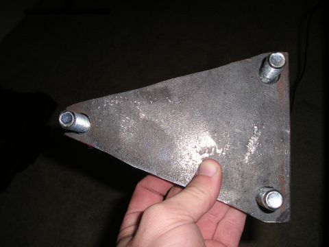 1996 Ford Bronco - A metal bracket with bolts is held in a hand against a dark background.