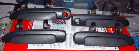 1997 Ford Crown Victoria - A set of four car door handles are displayed on a red box with printed material beneath them.