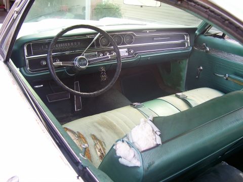 1965 Pontiac Catalina - The interior of a 1965 Pontiac Catalina shows its green vinyl seats and dashboard with visible wear and tear.