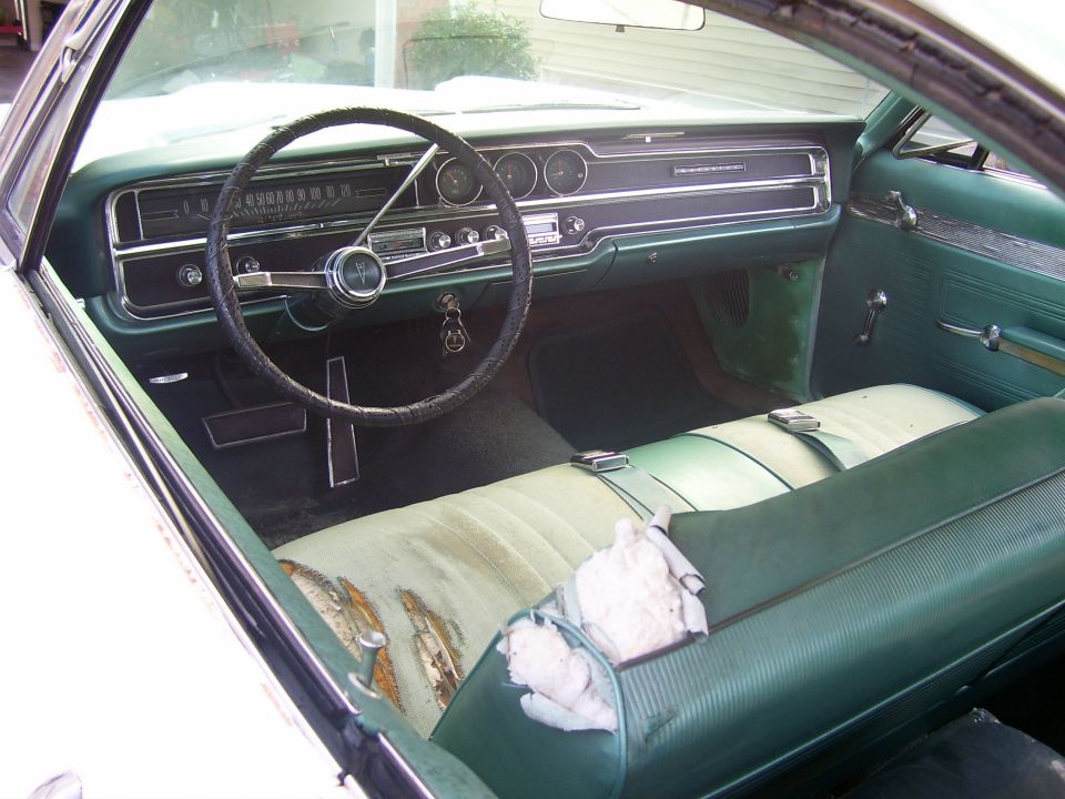 1965 Pontiac Catalina interior with green upholstery, cracked dashboard, and worn seats