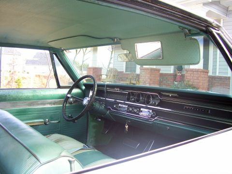 1965 Pontiac Catalina - The interior of a 1965 Pontiac Catalina features a two-tone green dashboard and upholstery, with a classic steering wheel and radio.