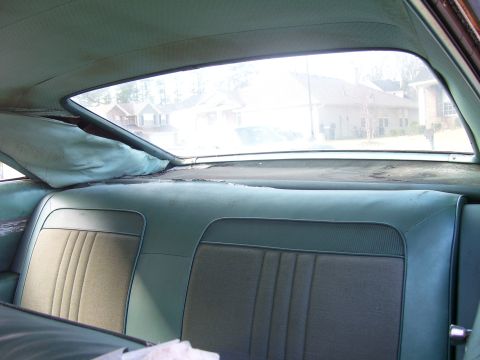 1965 Pontiac Catalina - The interior rear seat and headliner show signs of wear, with a view of houses through the rear window.