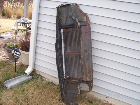 1965 Pontiac Catalina - A rusty radiator and grille assembly is shown outdoors, leaning against a house.