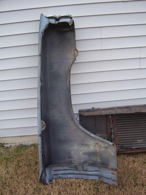 1965 Pontiac Catalina - A detached car fender and radiator are shown outdoors, leaning against a house.