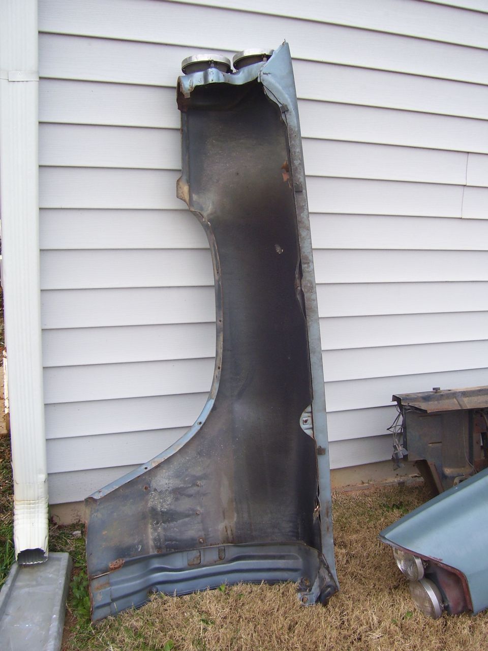 Fender part against a vinyl-sided wall