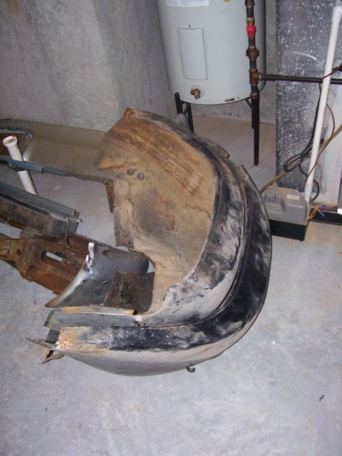 1965 Pontiac Catalina - This damaged car bumper is shown in a storage area with a water heater in the background.