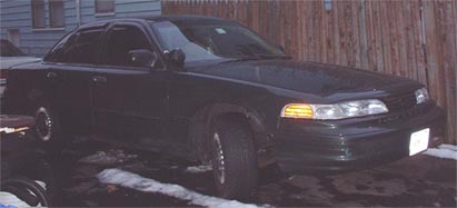 1997 Ford Crown Victoria - A dark sedan, likely a 1995 Ford Crown Victoria, is seen from a three-quarter front view with snow on the ground.