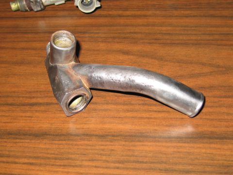 1991 Ford Crown Victoria LTD - A metal pipe fitting with a curved spout and threaded connections is shown on a wooden table.