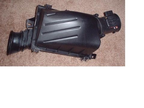 1997 Ford Crown Victoria - A black plastic air intake box is shown against a brown carpeted background.