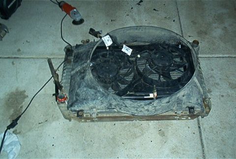 1986 Ford Bronco - A radiator assembly with dual electric fans is shown on a concrete floor, with an angle grinder and power cord visible.