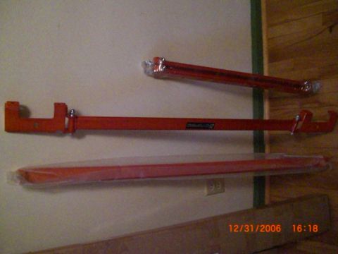 1993 Ford Probe - Three red metal bars are mounted on a wall, with one piece wrapped in plastic.