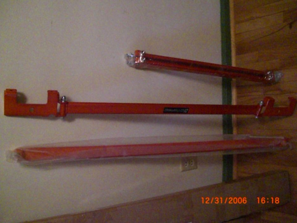 Three red metal bars mounted on a wall; one has a black label