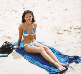 1997 Ford Crown Victoria - A woman in a bikini smiles while sitting on a towel at the beach.