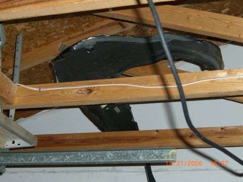 1993 Ford Probe - A car fender is stored in the attic, suspended between wooden beams.