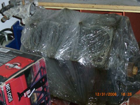 1993 Ford Probe - Engine block wrapped in plastic, with a box containing automotive parts visible in the foreground. The registry claims it is a 1993 Ford Pr…