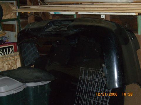 1993 Ford Probe - A black car bumper is stored in what appears to be a garage or workshop.