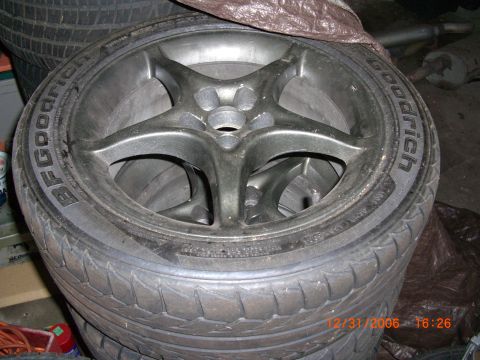 1993 Ford Probe - A close-up view of BFGoodrich tires and alloy wheels stacked together in what appears to be a garage or storage area.