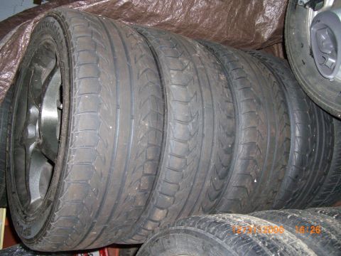 1993 Ford Probe - Several used tires are stacked together, with one tire and rim clearly visible on the left.
