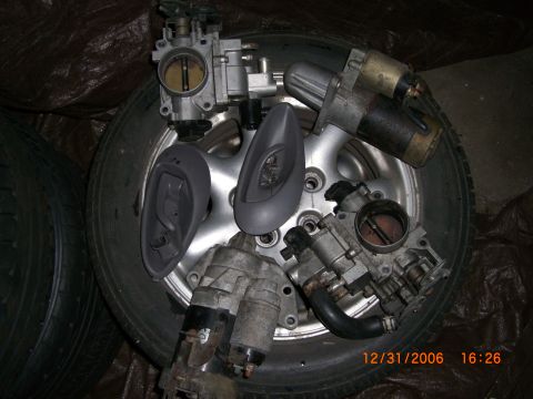 1993 Ford Probe - Various automotive parts, including throttle bodies and starters, are displayed on top of a tire.