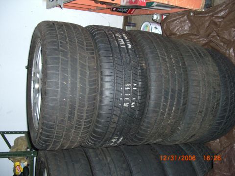 1993 Ford Probe - A set of four tires are stacked and leaning against a wall, with another set below.