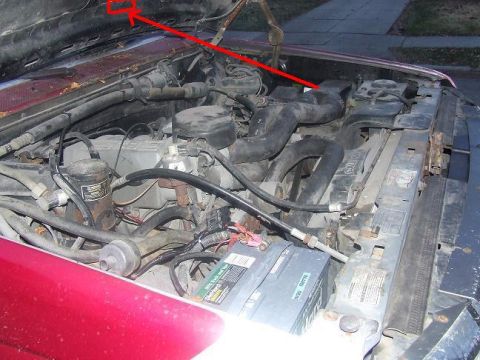 1992 Ford Bronco - The engine bay of a vehicle is shown with various components and a red arrow indicating a specific area.