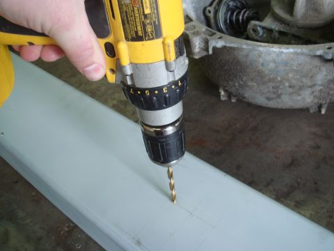 1996 Ford Bronco - A drill bit bores a hole into a metal piece, with a mechanical casing visible in the background.