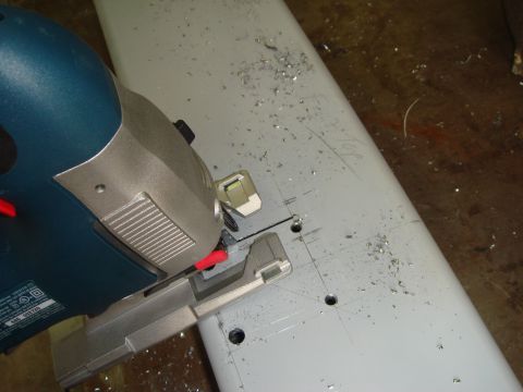 1996 Ford Bronco - A jigsaw is used to cut into a light gray metal component, creating metal shavings.