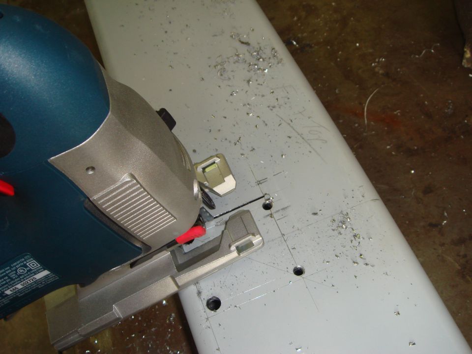 Jigsaw cutting a light gray metal piece with metal shavings scattered around