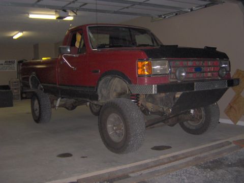 1990 Ford F-150 - This 1990 Ford F-150 pickup truck features a lifted suspension and a custom front bumper, suggesting off-road modifications.