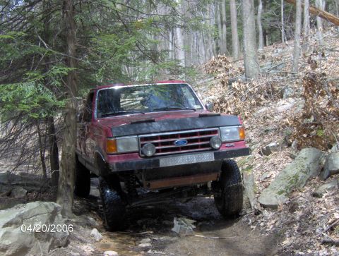 1990 Ford F-150 - This red 1990 Ford F-150 navigates a rocky, wooded trail.