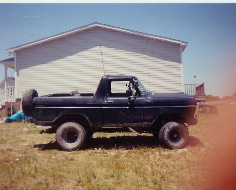 Side view of a black 1978 Ford Bronco parked in front of a house