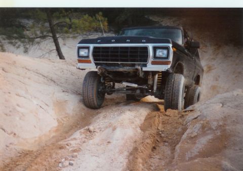 1978 Ford Bronco - A black 1978 Ford Bronco navigates a sandy, rutted trail during an off-road excursion.