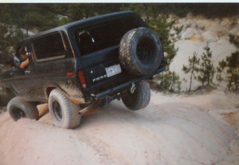 1978 Ford Bronco - This 1978 Ford Bronco is navigating a sandy terrain, showing its rear profile and spare tire.